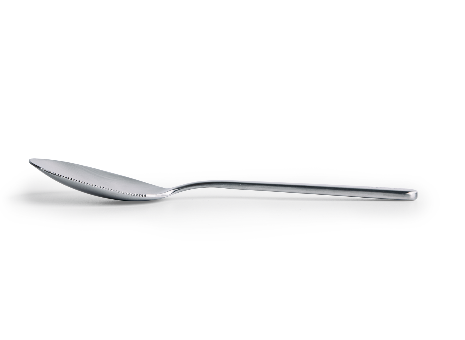 A serrated Misen stainless steel serving spoon is positioned horizontally on a white background, viewed from the side. The spoon has a deep, oval-shaped bowl with a serrated edge along the left half of its rim. The handle is slender and extends straight back from the bowl, with a slightly flattened end.