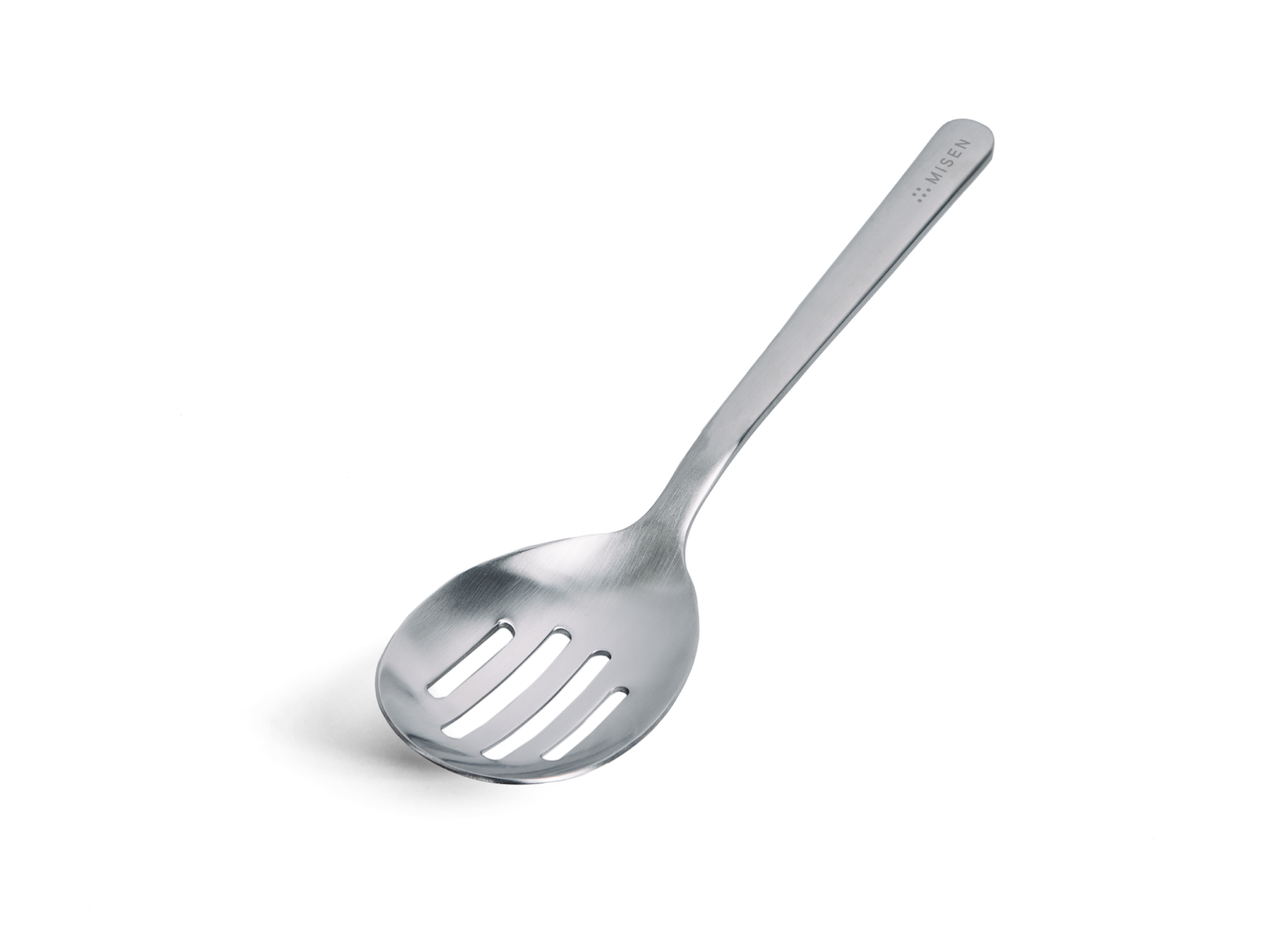 A Misen stainless steel slotted spoon is positioned diagonally against a white background, with its handle extending towards the upper right. The spoon has an oval-shaped head with four horizontal slots for drainage. It has a brushed finish.