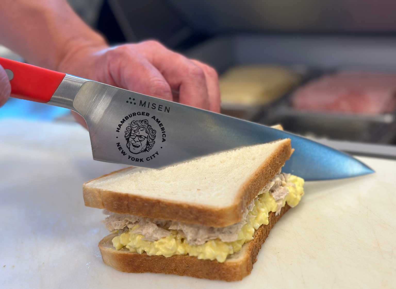 Using the Misen x George Motz - Hamburger America 8 inch Chef's Knife to cut a tuna & egg salad sandwich in half.