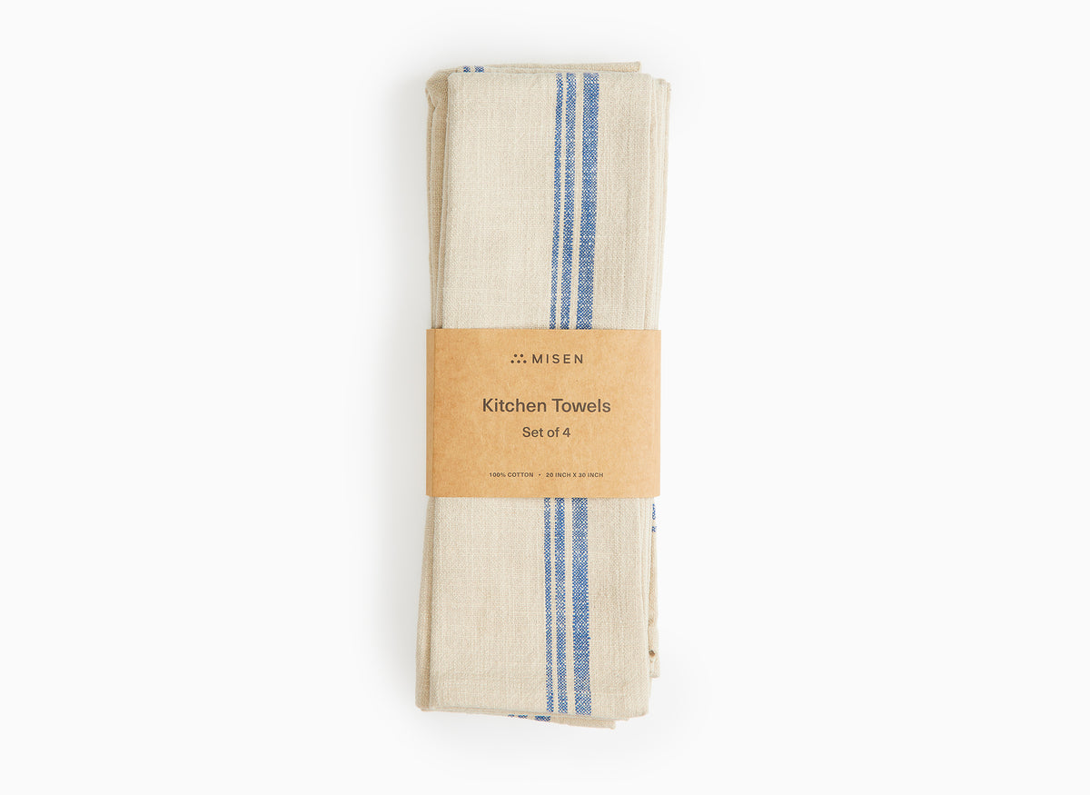 A set of blue Misen Kitchen Towels in their packaging lie flat on a white background.